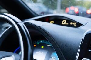 The dashboard displays various vehicle functions, including speed and fuel, as the rain obscures visibility while driving through heavy city traffic photo