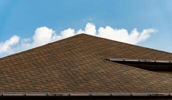 Bitumen tile roof. Newly built house roof top is covered with asphalt shingles. Building photo