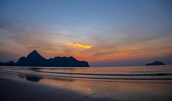 Golden light streams across the sea like threads of silk, and the beach, untouched and quiet, waits to welcome the new day. photo