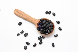 black beans seed on a wooden spoon on a white background photo