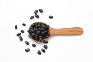 black beans on a wooden spoon on white background photo