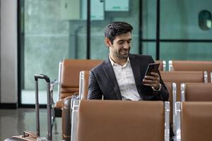 Caucasian businessman is using smart mobile phone while waiting in airline business departure lounge waiting for boarding airplane concept photo