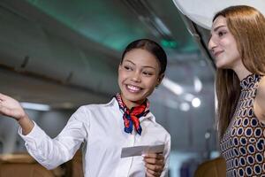 Flight attendant is welcoming and checking passenger boarding pass in business class and show the way to her seat for airplane flight and airline transportation photo