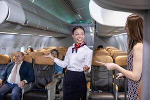 Flight attendant is welcoming and checking passenger boarding pass in business class and show her way to her seat for airplane flight and airline transportation photo