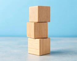 Stacking blank Three light wood blocks arranged in ascending size on a blue surface photo