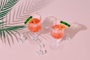 Summer layout with refreshing watermelon drink and palm tree leaves shadow on pink and white background. Sun and shadows. Minimal cocktail concept. Trendy summertime party idea. Summer aesthetic. photo
