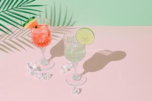 Summer scene with watermelon and lime drinks and palm leaves shadow on pink and green background. Sun and shadows. Minimal cocktail concept. Trendy summertime party idea. Summer aesthetic. photo