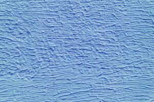 A wall with a blue paint that has a texture. The texture is made up of lines and swirls. photo