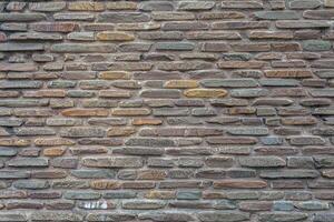 The wall of the castle is made of uneven, flat stones of various dark shades. Abstract dramatic background. photo