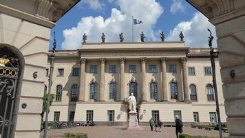 Berlin Germany 25.05.2025, Humboldt University Building With Classical Columns, Latin Inscription, Student Activity, Flag And Wilhelm Von Humboldt Statue In video