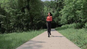 Woman Jogging Through Forest Pathway In Sportwear On Sunny Day, Running With Focused Breathwork Surrounded By Green Trees And Nature video