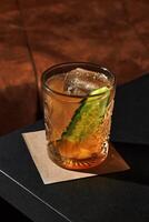 Refreshing cocktail with cucumber and ice in elegant glass on bar counter photo