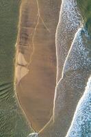 drone shot capturing the delicate foam lines where sea meets shore at sunset, aerial top down image by drone. Summer background concept photo