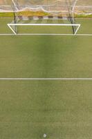 aerial view of an empty soccer goal on a green artificial turf field, aerial drone top down view photo