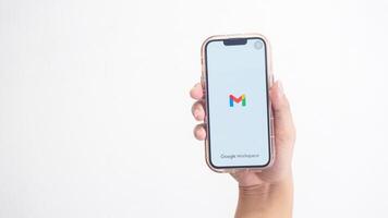 Yogyakarta, Indonesia, 2025 - Hand holding smartphone that shows opening page of Gmail application, an email or webmail service platform, on screen isolated on white background photo