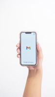 Yogyakarta, Indonesia, 2025 - Hand holding smartphone that shows front page of Gmail application, an email or webmail service platform, on screen isolated on white background photo
