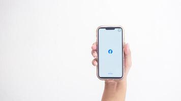 Yogyakarta, Indonesia, 2025 - Hand holding smartphone that shows opening page of Facebook application, a social networking service platform, on screen isolated on white background photo