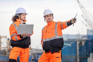 Maritime Safety Engineer Working at Port Terminal with Laptop and Walkie-Talkie, Industrial Engineers Collaborating at Harbor Site, Dock Worker in Safety Uniforms Using Technology for Port Operations photo