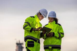 Engineers with Tablet at an Industrial Plant at Dusk, Two Industrial Workers Collaborating On-Site, Professional Engineers Overseeing Operations at a Refinery photo