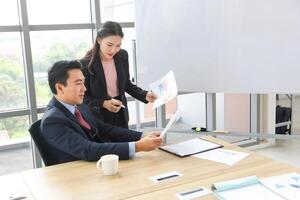 Business Professionals Reviewing Charts in a Modern Office, Colleagues Analyzing Data in a Boardroom, Asian Businesspeople Discussing Financial Reports photo