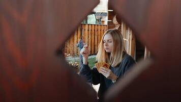 Young blonde woman enjoying card game on cozy terrace, casually dancing while drawing playing card from deck. playing cards inspire leisure. Concept of tabletop games, leisure, and emotional joy. video