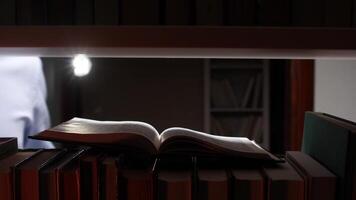An open book on a shelf with a flashlight video