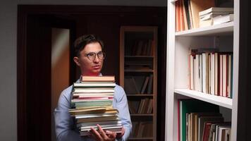 A man holding a stack of books in front of a bookcase video
