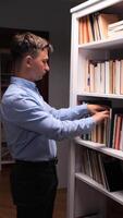 A man is standing in front of a bookcase with books video