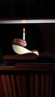 A person holding a lit candle in front of a book video