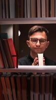 A man holding a cup in front of a shelf of books video