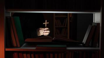 A person holding a cross in front of a book shelf video