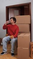 vertical Man drinking water and eating banana while taking a break from moving into apartment video