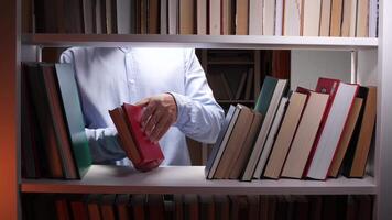 A man is holding a book in front of a shelf full of books video