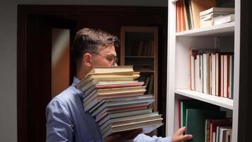 A man is holding a stack of books in front of a bookcase video