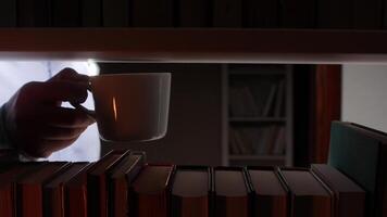 A person holding a cup of coffee in front of a stack of books video