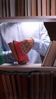 A man is holding a book in front of a shelf of books video