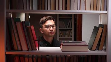 Young male priest selecting a holy book from a shelf in a church library, surrounded by rows of books and a wooden cross, embodying devotion and spirituality in the evening light video