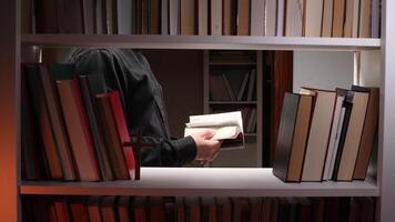 A man is standing in front of a book shelf with a book in his hand video