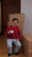 vertical close-up Man drinking coffee while relaxing during move to new home video