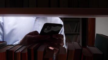 A man holding a cell phone in front of a stack of books video