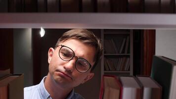 A man in glasses looking at books on a shelf video