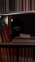 A person in a black mask peeking out from behind a book shelf video