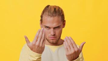 A young man with mixed heritage displays a fierce and determined expression. He stands against a bright yellow background, showcasing his confident demeanor and readiness for action. video