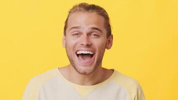 A young man with a joyful expression showcases his happiness while dressed casually. His light brown hair complements the bright yellow backdrop, creating a vibrant atmosphere. video