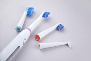 The one white modern electric ultrasonic toothbrush on the gray surface. photo