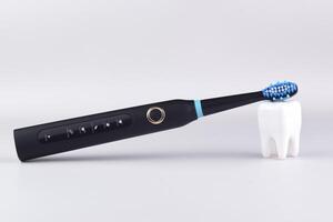 One black modern electric ultrasonic toothbrush on the gray surface. photo