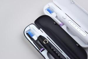 The white and black electric ultrasonic toothbrushes on a gray surface photo