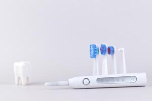 One white modern electric ultrasonic toothbrush on the gray surface. photo