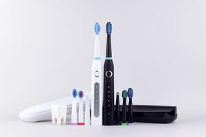 Two modern electric ultrasonic toothbrushes on a gray surface photo