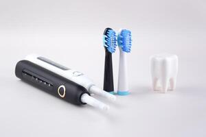 White and black modern electric ultrasonic toothbrushes on a gray surface photo